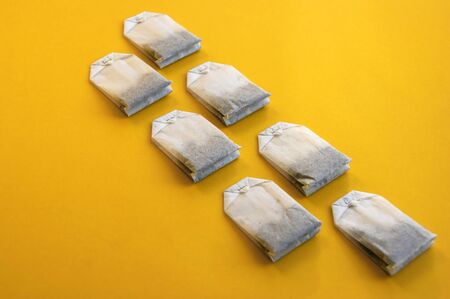 A lot of disposable tea bags on a yellow background.