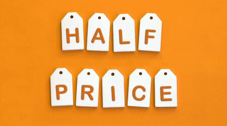 Nine white wooden tags with the word HALF PRICE on a orange background. Sales concept.