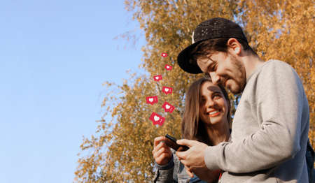New alerts on a mobile phone, a happy young couple, opening social networks to view messages, likes, comments. Copy space.の写真素材