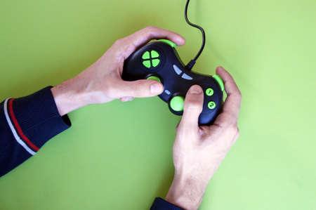 Male hands hold a gamepad in light green background. Minimalism. Game concept.