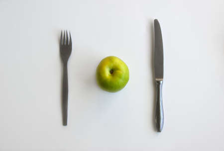 Green apple with knife and fork on white background top view. Diet concept and healthy lifestyleの写真素材