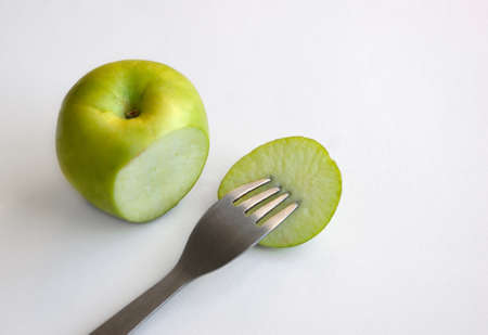 Incision green apple with fork on white background top view. Diet concept and healthy lifestyleの写真素材