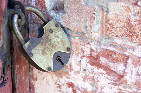An old padlock on closed doors, a rusty lock on the gate. Brick wall.の写真素材