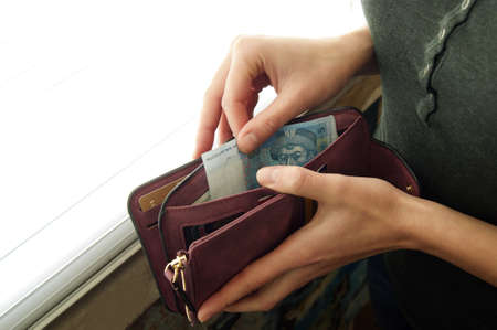 Female hands considers Ukrainian hryvnia in a small cash wallet.
