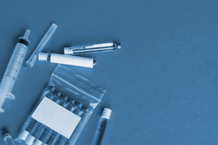 Vials with a cure for the disease, 3 ml, a plastic syringe with a needle. Blue tinted photo. Concept vaccinations.の写真素材