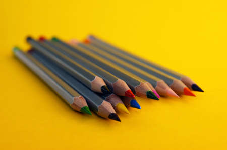 Many colorful pencils laying on a beautiful yellow background. Selective focus.の写真素材