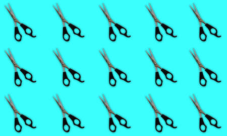 Composition on a turquoise background with many professional hairdressing scissors for haircuts.
