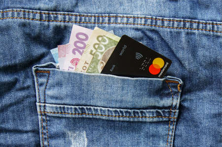 KHARKOV, UKRAINE - FEBRUARY 19, 2020: Ukrainian banknotes and a Credit Card Master Card in the back pocket of jeans. Contactless electronic payment concept.のeditorial素材
