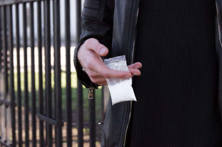 Man hand holds plastic packet with cocaine or another drugs, drug abuse and danger addiction...