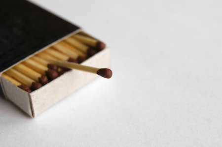 Long wooden safety matchsticks stacked in cardboard matchbox on white background.