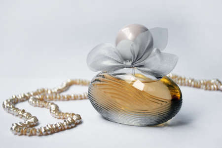 Perfume bottle with pearl on light background. Perfumery, cosmetics, fragrance collection.