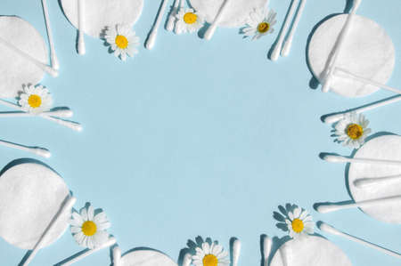 Ear sticks, white cotton pads and chamomiles on a blue background with copy space. Concept body hygiene and personal care.の写真素材