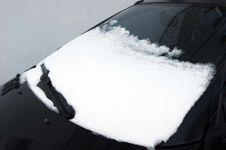Frozen car covered snow at winter day, view front window windshield on snowy background.
