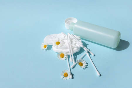 Ear sticks, white cotton pads and chamomiles on a blue background with copy space. Concept body hygiene and personal care.の写真素材