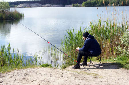 A lonely young guy goes fishing in the warm season. Interesting hobby.の写真素材