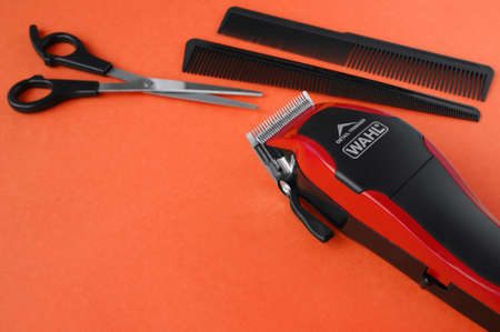 KHARKOV, UKRAINE - JULY 2, 2020: Hairdressers tool. Hair clipper WAHL close-up on a red background with scissors and combs.のeditorial素材
