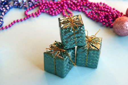 Christmas decoration for the Christmas tree in the form of small shiny gifts on a blue background.