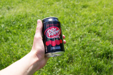 KHARKOV, UKRAINE - JUNE 12, 2020: Hand holds metal can of Dr. Pepper on a background of green grass.のeditorial素材