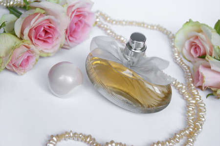Perfume bottle with rose and pearls on a light background. Perfumery, cosmetics, fragrance collection.の写真素材