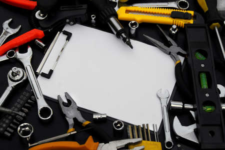 Notebook for writing, around various work tools on a black background. Repair and construction...