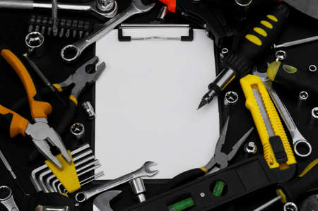 Notebook for writing, around various work tools on a black background. Repair and construction concept.の写真素材