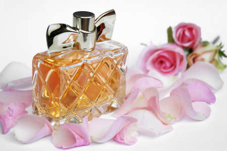 Perfume bottle with rose petals and pearls on a light background. Perfumery, cosmetics, fragrance...