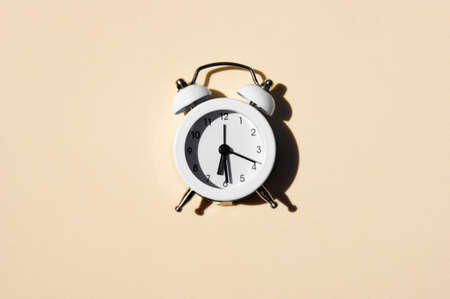 White vintage alarm clock with shadow - flat lay.