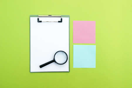 Magnifying glass, clipboard and colorful stickers. Office background or information search, study and school concept.の写真素材