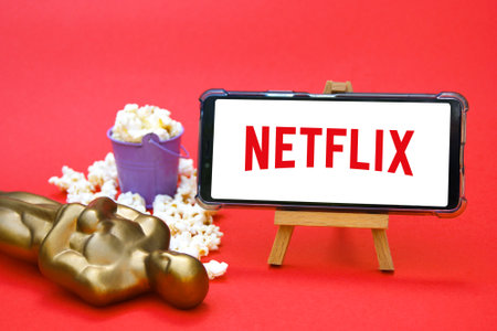 KHARKIV, UKRAINE - JUNE 1, 2020: Smartphone with Netflix studio logo, Oscar figure and popcorn. Film...