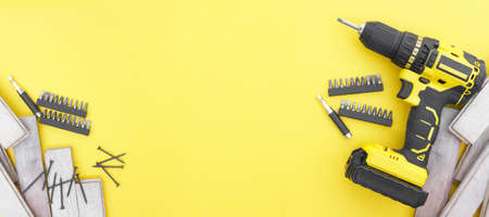Yellow-black screwdriver on a yellow background, screws, a set of bits. Copy space.