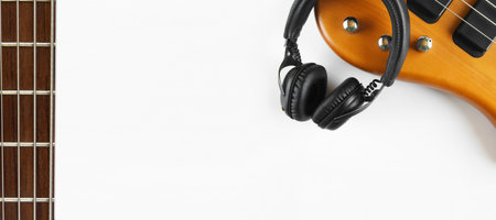 Portable black headphones and bass guitar on white background.の写真素材