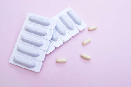 Gynecological medicines for women's health in form of suppository, capsules on pink background. Vulvovaginal infections treatment. Top view.の写真素材