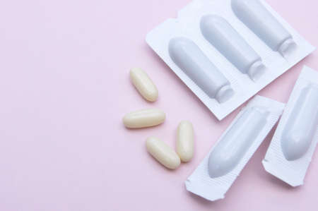 Gynecological medicines for women's health in form of suppository, capsules on pink background....