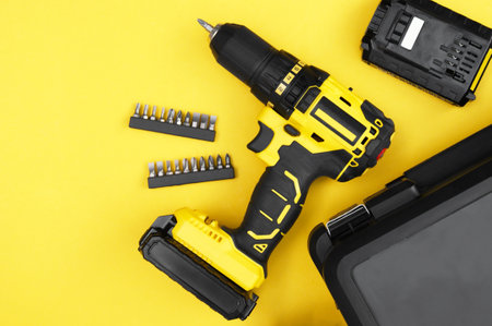 Yellow-black screwdriver on a yellow background, a set of bits.