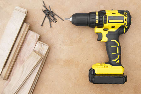 Yellow-black screwdriver on wood background, screws. Parquet boards.
