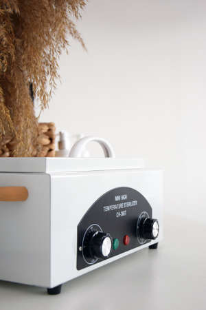 Mini high temperature sterilizer on the white background. Medical and beauty equipment for steam sterilization, instrument disinfection from bacterial and viral infections.の写真素材