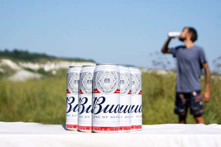 KHARKIV, UKRAINE - AUGUST 1, 2021: Many cans of Budweiser Lager Alcohol are set against the backdrop of the landscape. Budweiser is America's most popular Anheuser-Busch Inbev brand.のeditorial素材