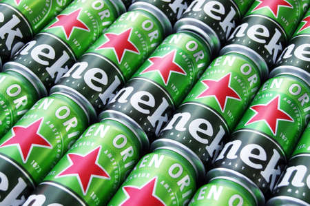 KHARKIV, UKRAINE - AUGUST 1, 2021: Many cans of Heineken alcoholic beer lie on a gray background. Heineken is a Dutch brewing company, the largest in the country and the second largest in the world.のeditorial素材
