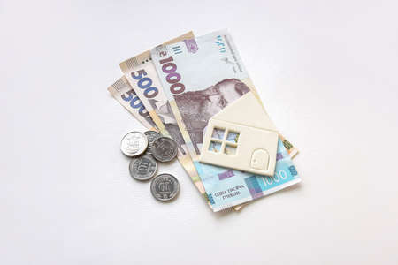 New banknotes in denominations of 500 and 1000 hryvnia and a small white paper house. The concept of rent and utility bills.の写真素材