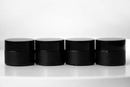 Several black jars of face cream on a white background. Beauty care concept.の写真素材