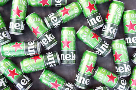 KHARKIV, UKRAINE - AUGUST 1, 2021: Many cans of Heineken alcoholic beer lie on a gray background....