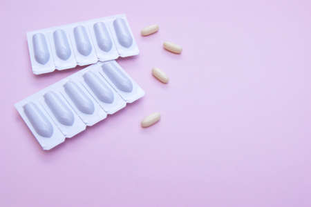 Gynecological medicines for women's health in form of suppository, capsules on pink background....