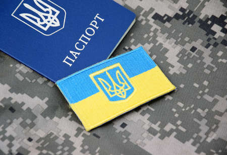 Ukrainian passport and flag with the coat of arms of Ukraine on the background of military camouflage. War in Ukraine. stop war.の写真素材