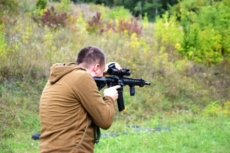 A young guy is trained in combat shooting from a rifle AR 15.