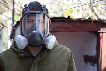 A young guy in a respirator in a bomb shelter. dark photo. Personal safety from  toxic work,...