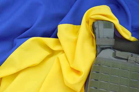 Tactical, military body armor with plates on the background of the flag of Ukraine. The concept of protecting the body from shots in the war in Ukraine.の写真素材