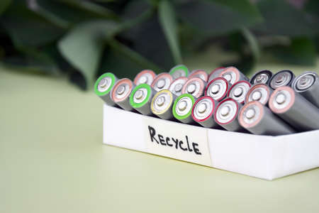 Used AA batteries and proper disposal of environmentally and soil-toxic batteries on a green...