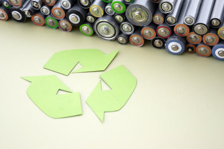 Used AA batteries and proper disposal of environmentally and soil-toxic batteries on a green background. The concept of processing harmful and recyclable objects.の写真素材