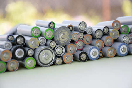 Used AA batteries and proper disposal of environmentally and soil-toxic batteries on a green background. The concept of processing harmful and recyclable objects.の写真素材
