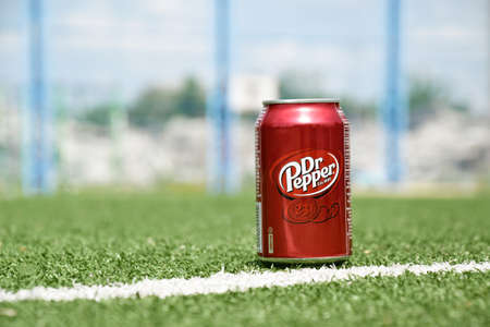 Kharkiv, Ukraine - June 1, 2022: A metal can of Dr. Pepper stands against a background of green...